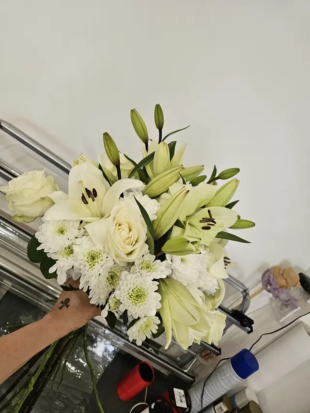 Bouquet de lys blancs et roses crème tenu à la main