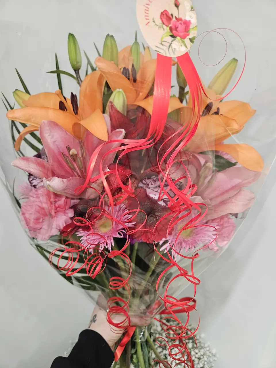 Bouquet de lys orange et gerberas roses tenu à la main