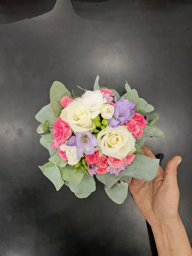 Petit bouquet rond de roses tenu à la main