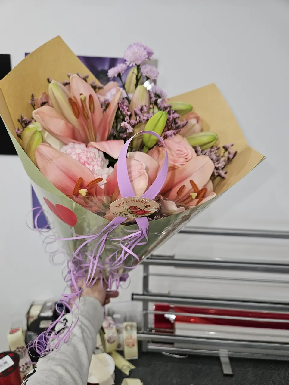 Bouquet de lys roses dans un papier kraft tenu à la main