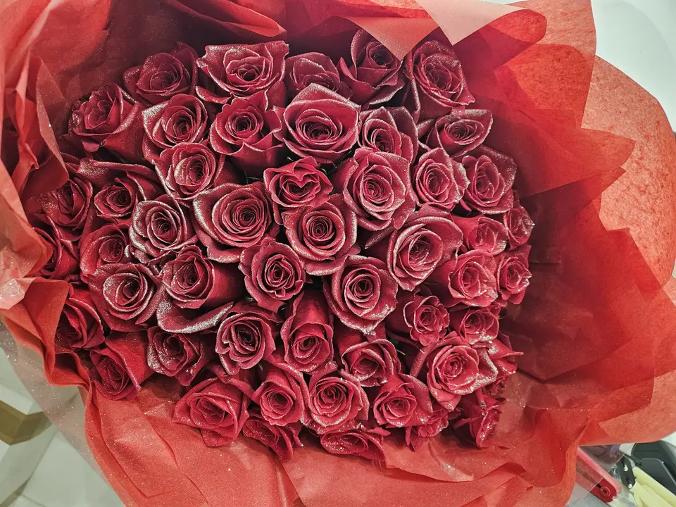 Bouquet de roses pailletées dans un papier rouge
