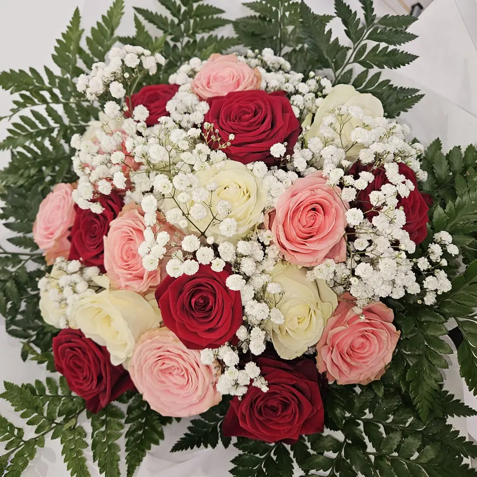 Bouquet rond de roses rouges et roses pâles ponctué de gypsophile