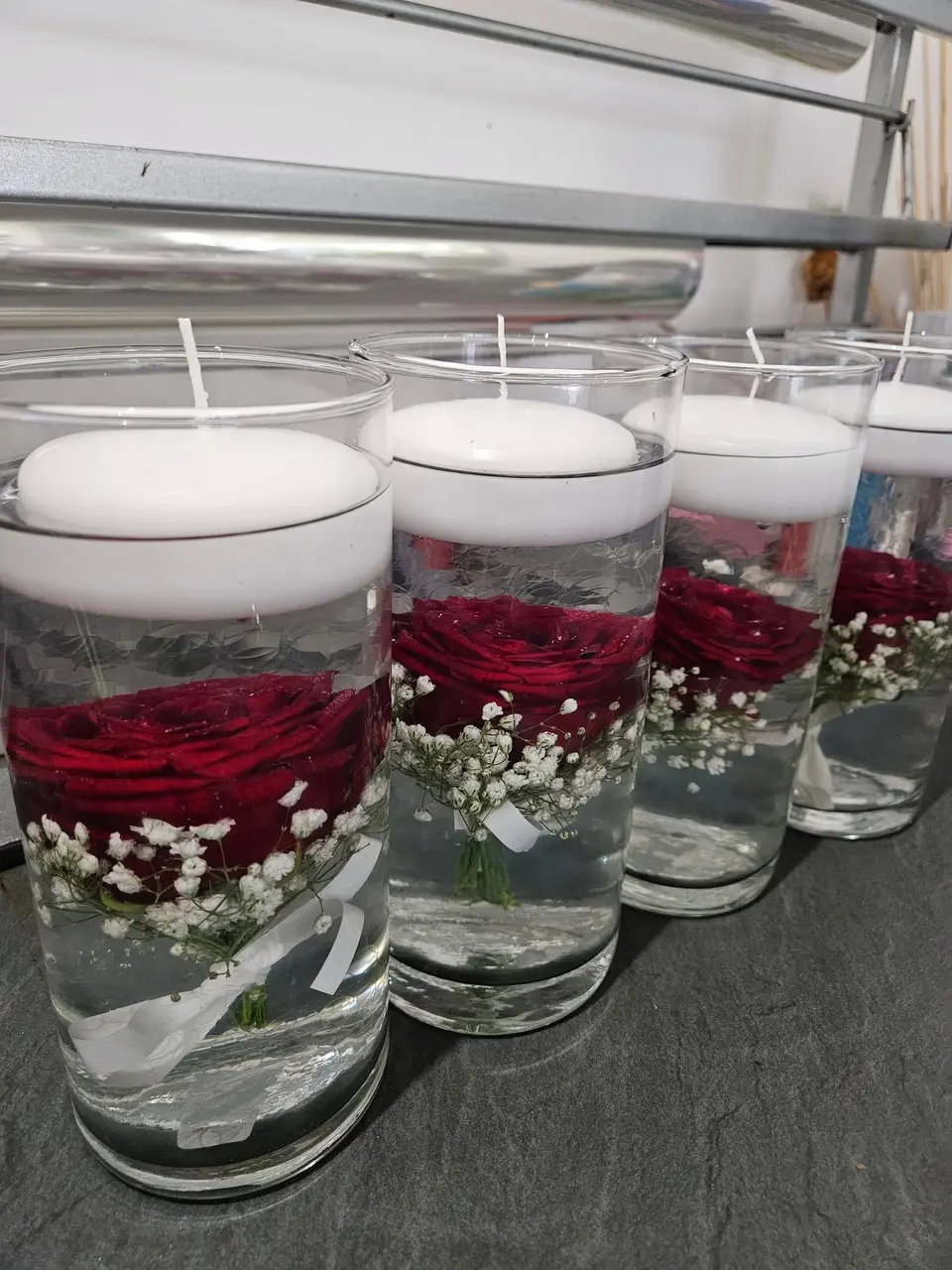 Centres de table : roses rouges et gypsophile immergées sous bougies flottantes