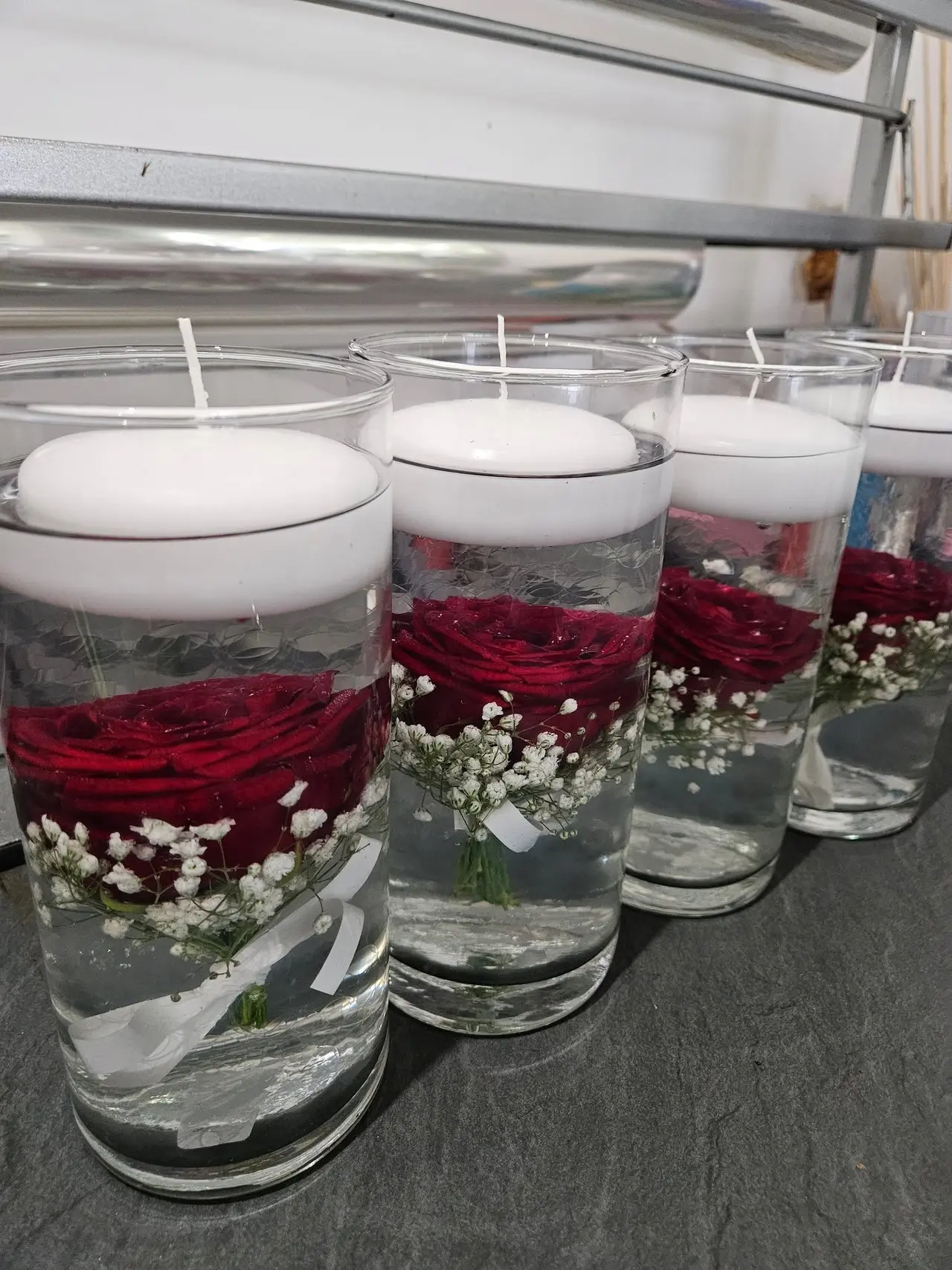 Centres de table : roses rouges et gypsophile immergées sous bougies flottantes