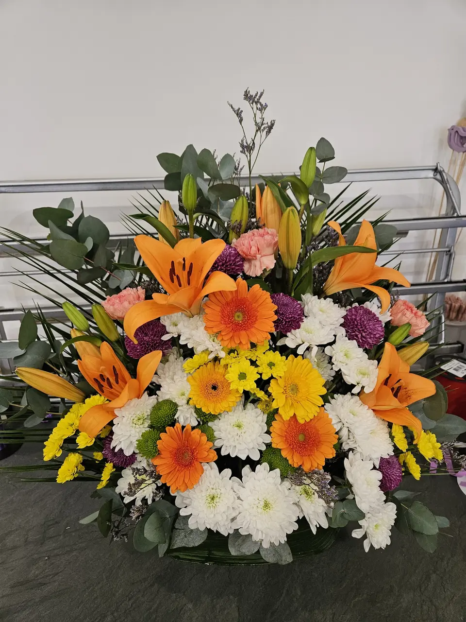 Composition piquée orange et jaune avec lys, gerberas et chrysanthèmes