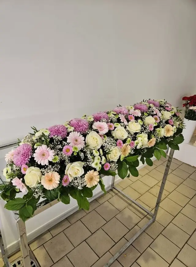 Dessus de cercueil pastel : chrysanthèmes roses, roses blanches, gerberas abricot et gypsophile