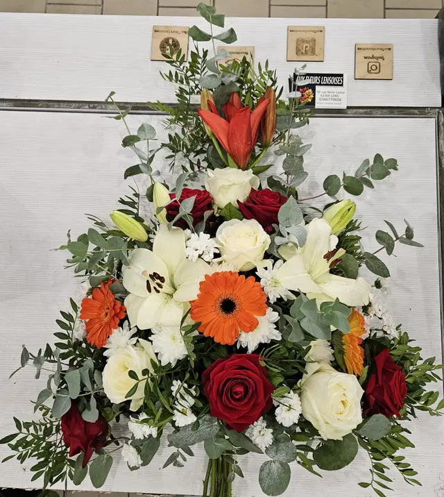 Gerbe de deuil blanche relevée de gerberas orange et roses rouges