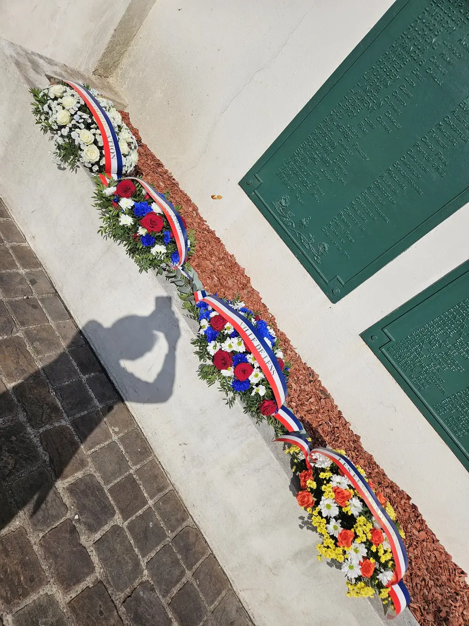 Gerbes de commémoration alignées devant un mémorial